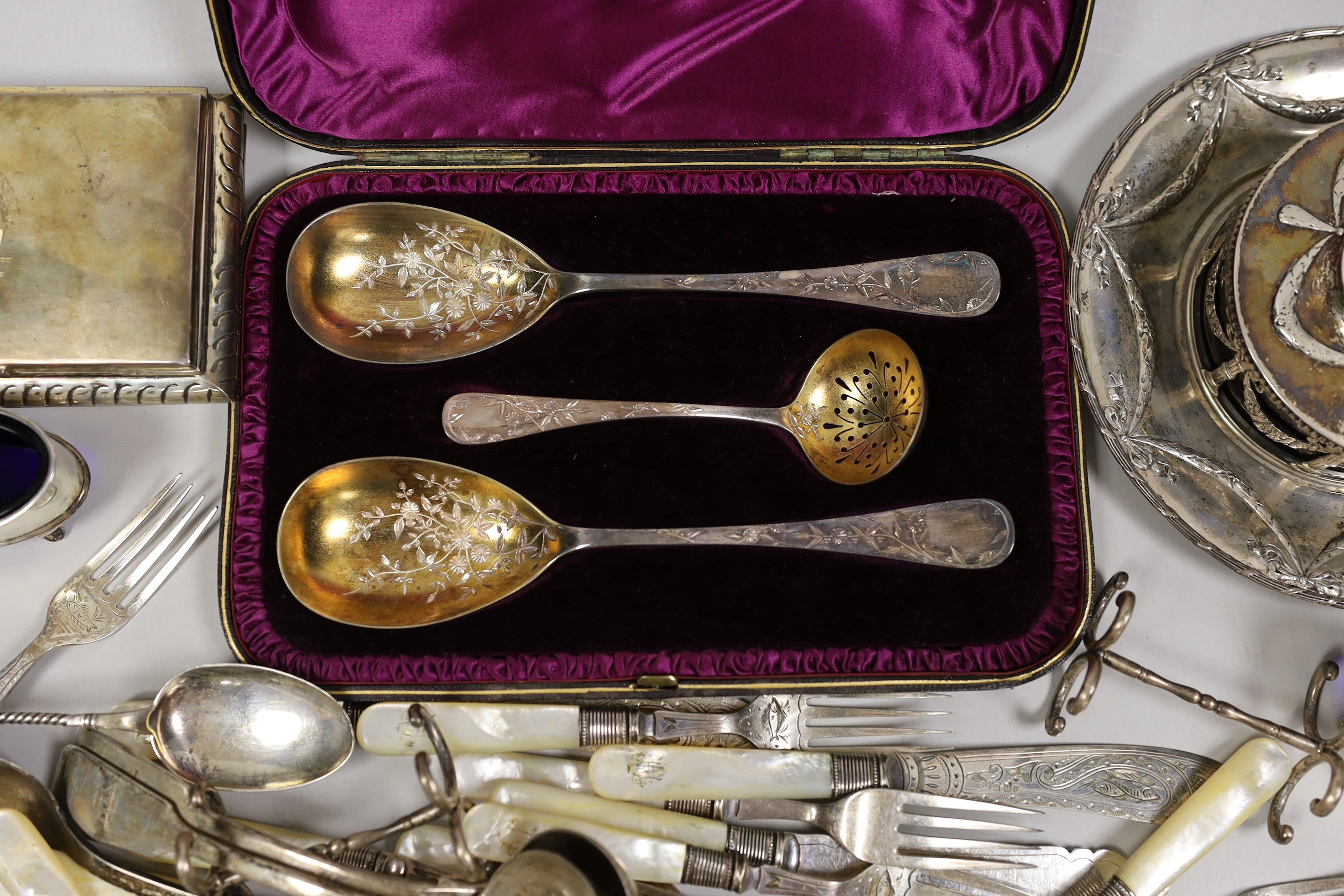 A late 19th century Hanau white metal butter dish stand, with blue glass liner, diameter 18.3cm, a sterling mounted cigarette box, a cased Victorian three piece silver cutlery dessert set, a pair of Victorian silver fidd